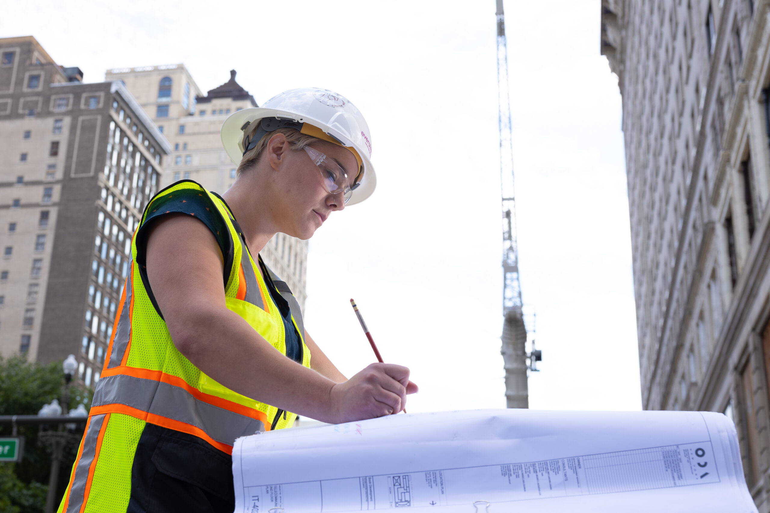 a woman in a safety vest and hat looking at plans